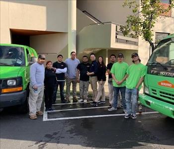 This is 10 of our team members standing next to work vans in front of a commercial building.